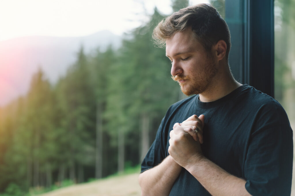 7 Bible Verses about Generosity-young man praying near beautiful panorama