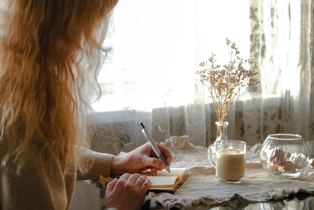 7 Bible Verses about Generosity-a woman journaling at a table with coffee and flowers