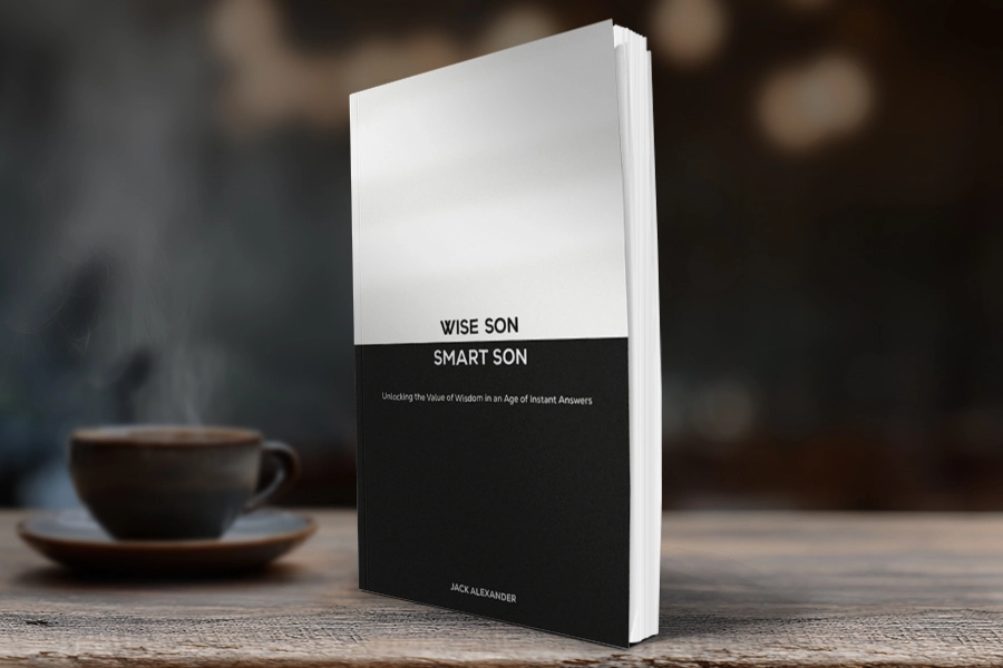 A book mockup titled "WISE SON SMART SON" stands on a wooden table, featuring a minimalist black-and-white split cover design with a blurred coffee cup in the background.
