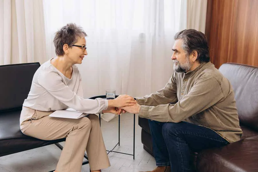A caring woman carefully holding a man’s hands