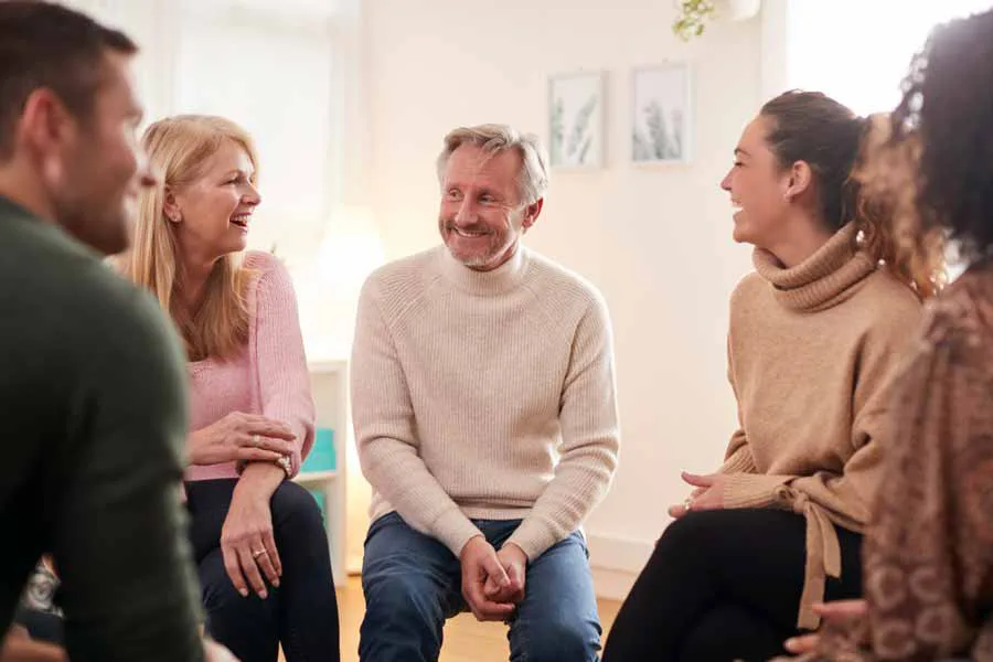 A man smiling at a support group meeting with community members