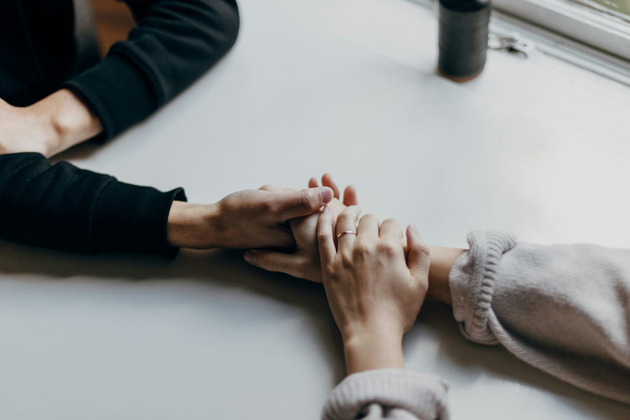 Two people holding hands across a table, still showing love after a hard conversation.