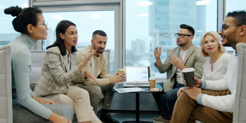 A team of office workers sitting in a circle gesturing expressive points during an intense group discussion.