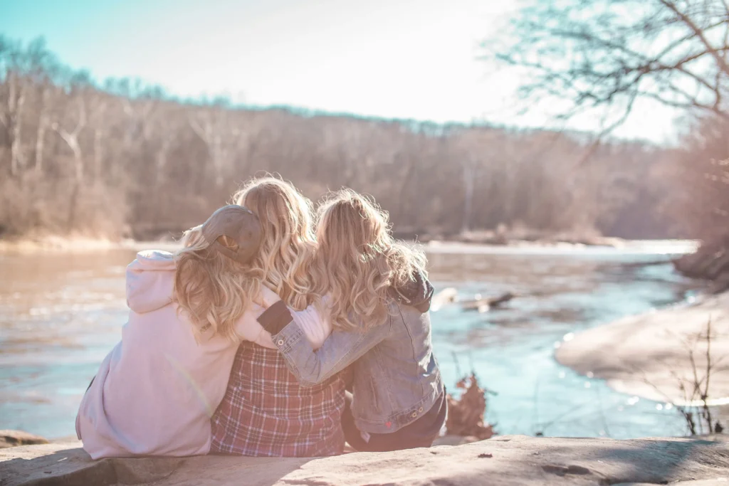 Three friends sit together with their arms around each other for support.