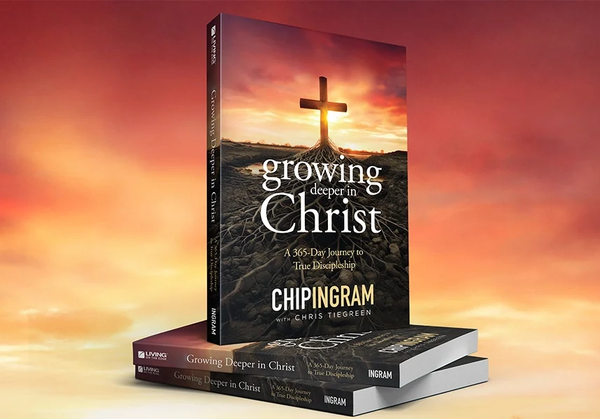 A stack of the devotional book "Growing Deeper in Christ" by Chip Ingram and Chris Tiegreen, featuring a cover with a cross rooted in the earth against a sunset sky.